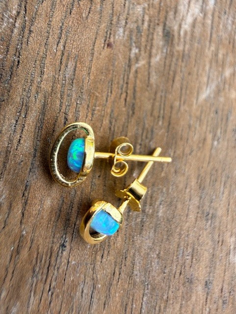 Gold earrings with blue gemstones on a wooden surface