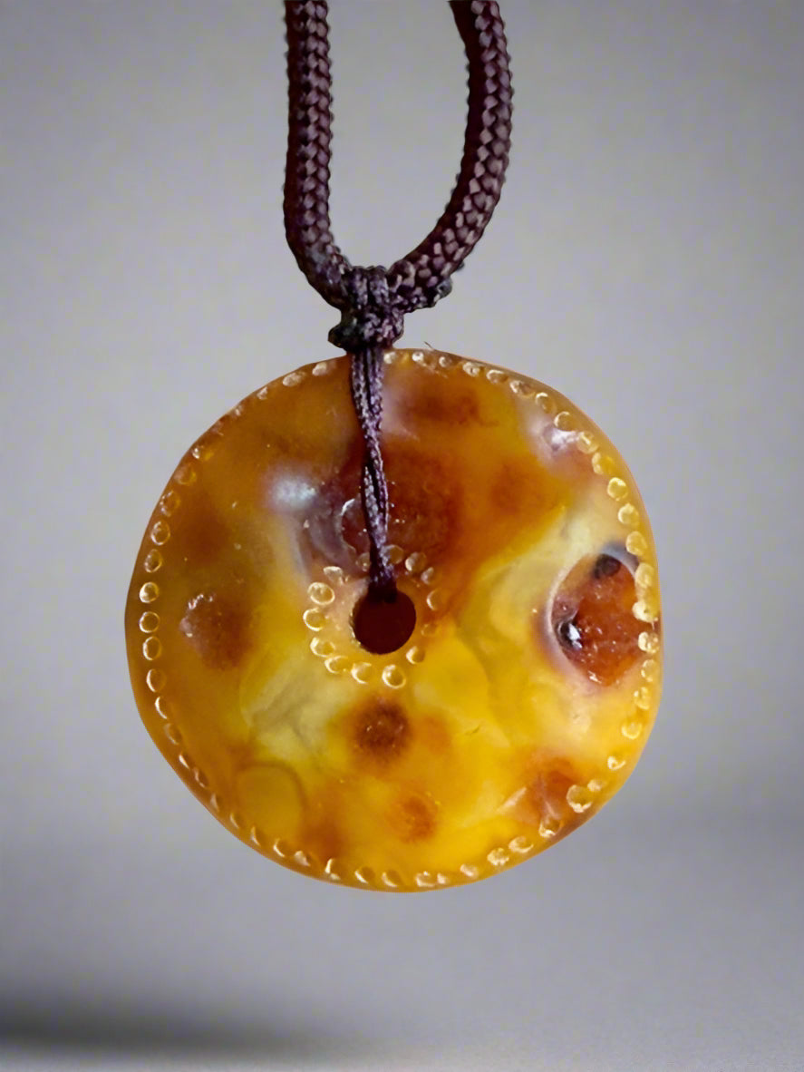 Round amber-colored pendant on a string against a beige background