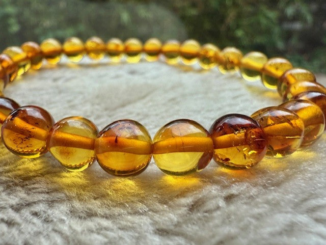 Adult Honey Baltic Amber Bracelet on a textured surface with a blurred natural background