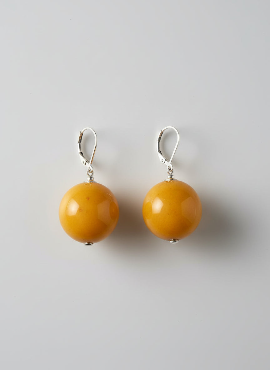 Pair of amber-colored earrings on a light gray background