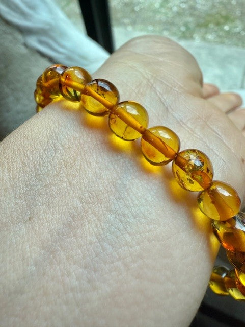 Amber-colored beaded bracelet on a wrist with a blurred background