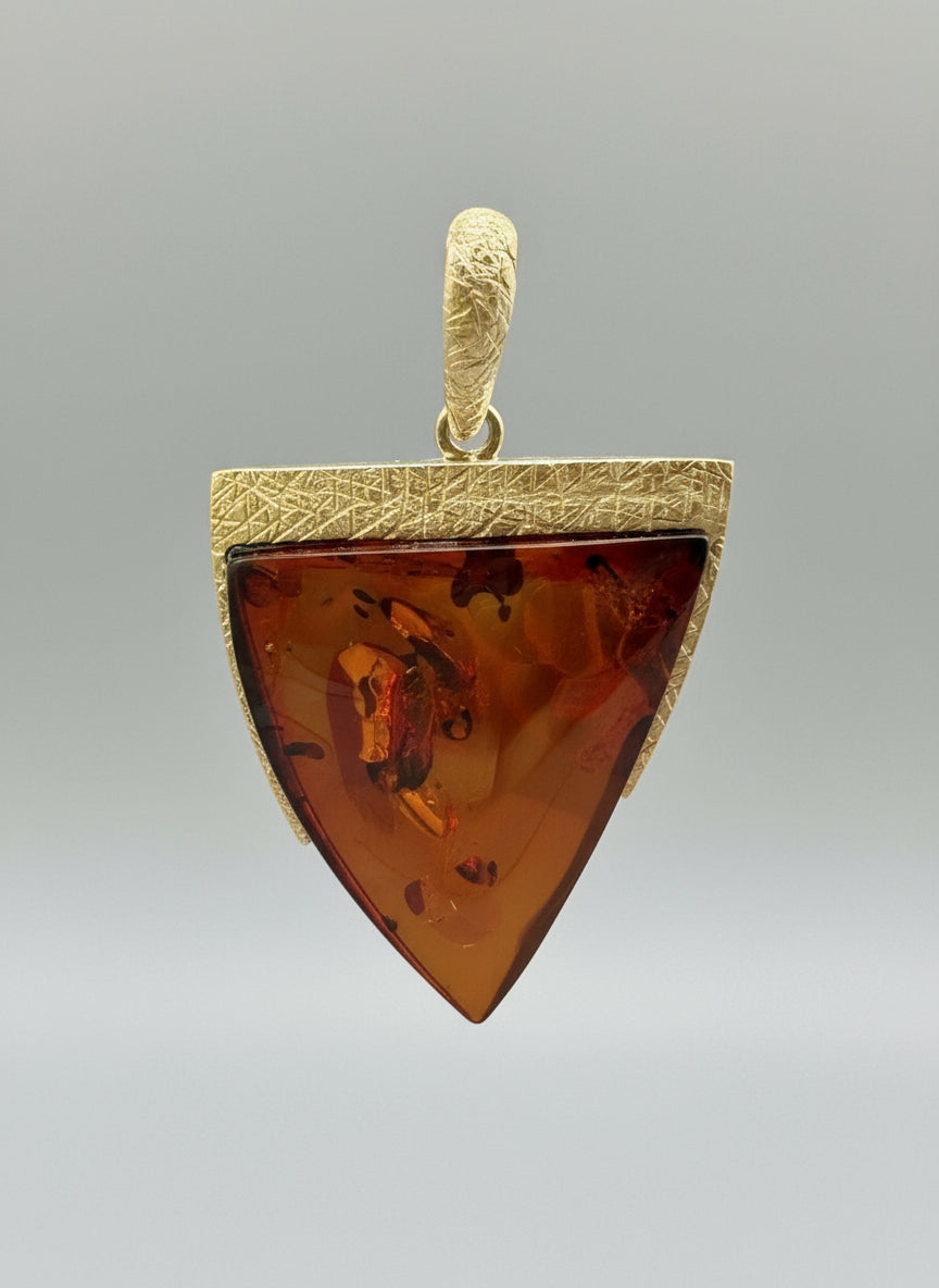 Amber-colored pendant on a branch with a blurred green background