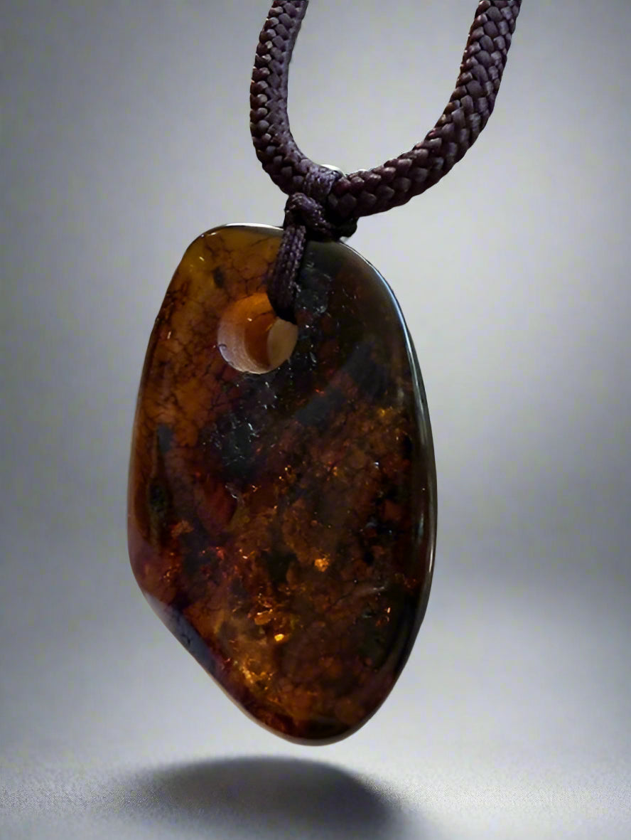 Amber pendant on a dark cord against a neutral background