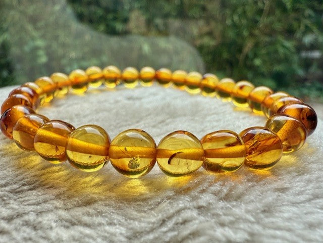 Adult Honey Baltic Amber Bracelet on a textured surface with a blurred natural background