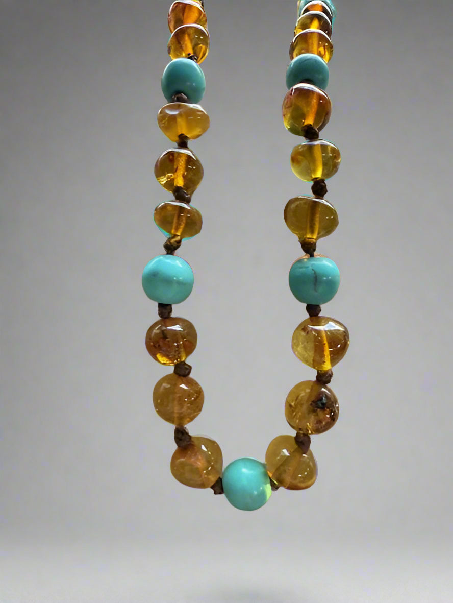 Necklace with alternating turquoise and amber beads on a gray background