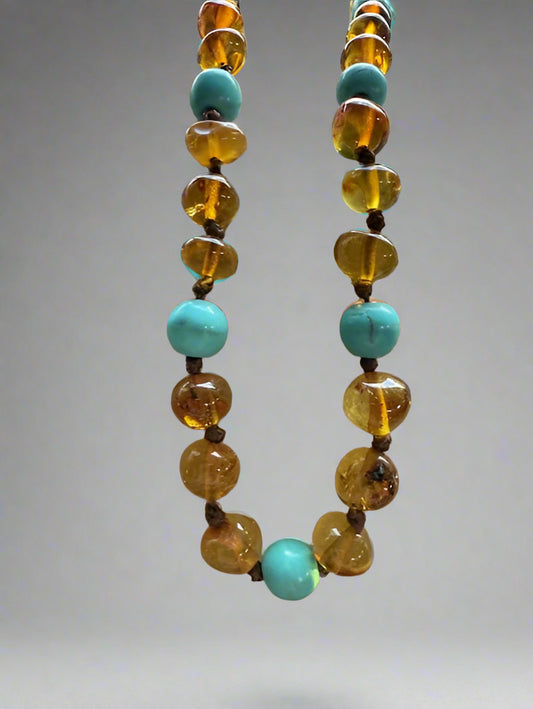 Necklace with alternating turquoise and amber beads on a gray background