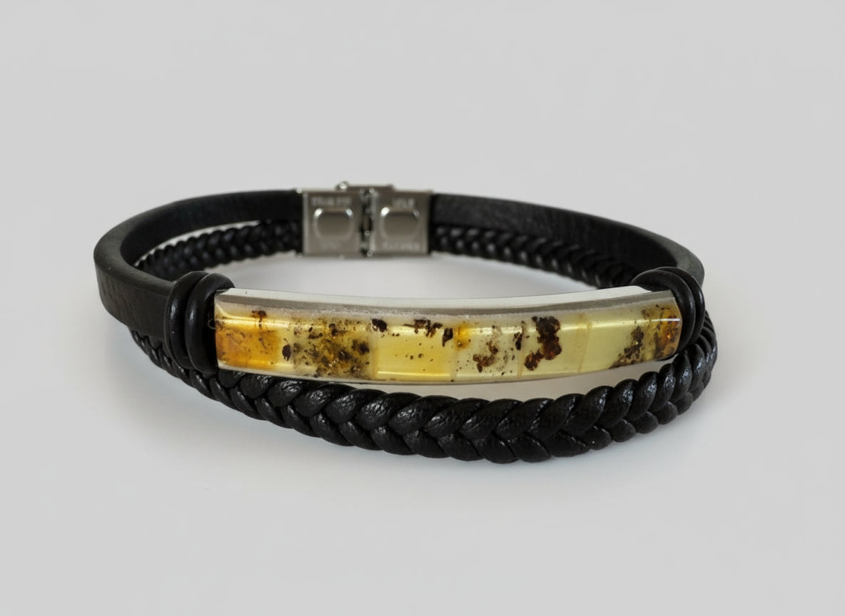 Bracelet with black braided strap and silver and amber inlay on a light surface.