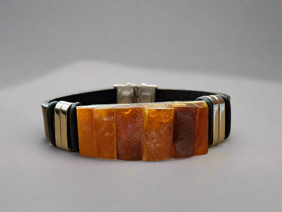 Amber bracelet with black and silver accents on a wooden surface outdoors