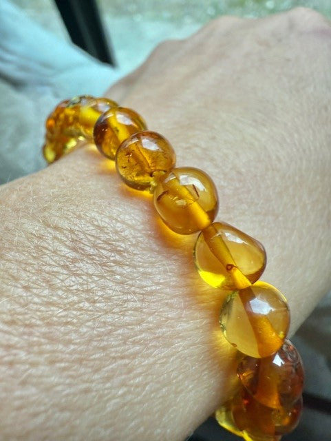 Amber beaded bracelet on a wrist with a blurred background