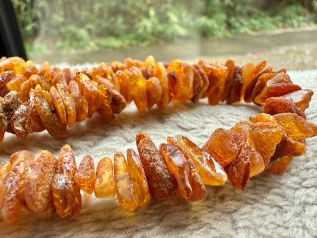 Amber necklace on a textured surface with a blurred natural background