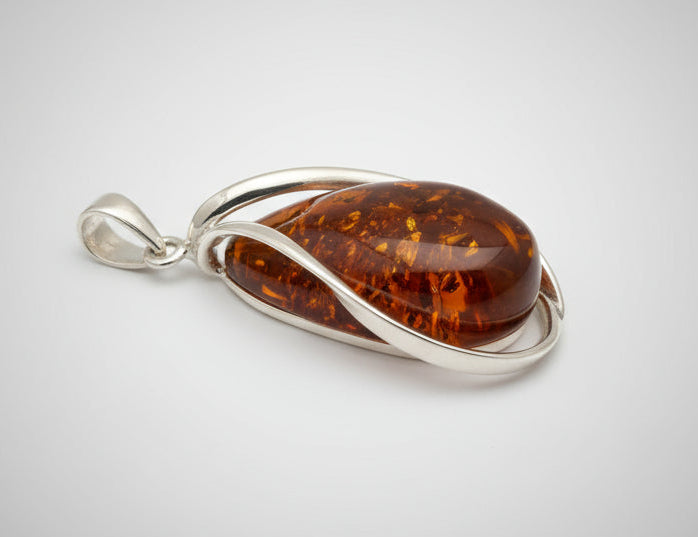 Amber pendant with silver setting on a wooden surface