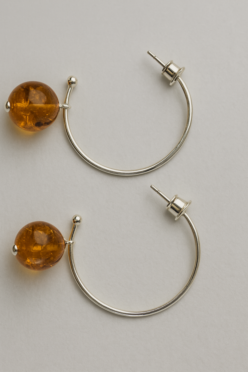 Pair of hoop earrings with amber beads on a light gray background
