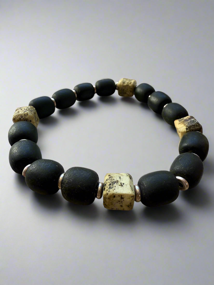Black beaded bracelet with gold accents on a textured surface