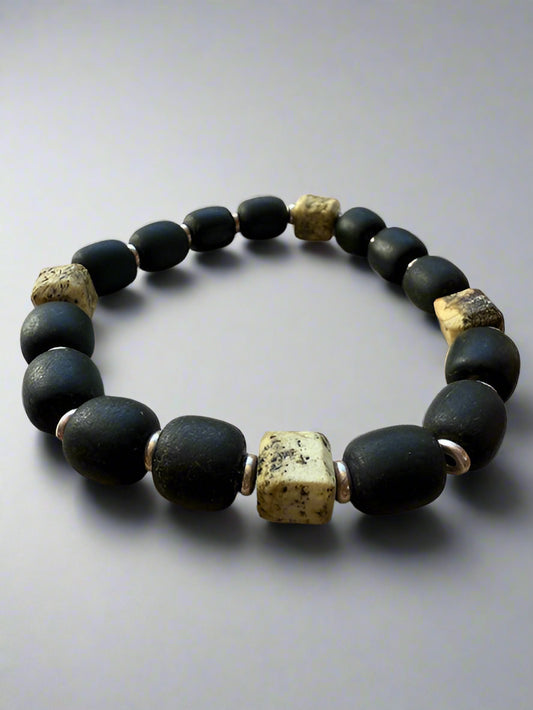 Black beaded bracelet with gold accents on a textured surface