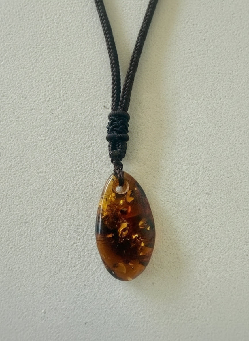 Teardrop-shaped amber pendant on a string against a light background