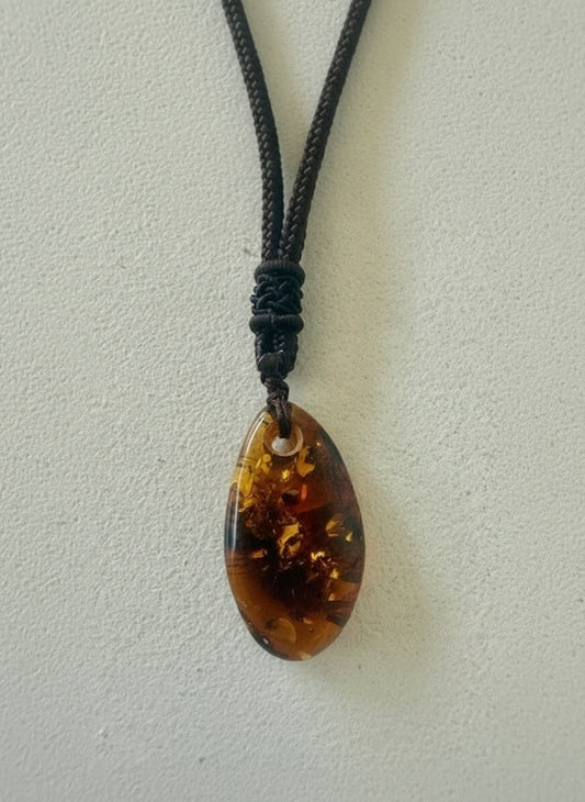Teardrop-shaped amber pendant on a string against a light background