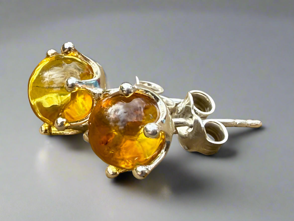 Pair of amber stone earrings with silver settings on a wooden surface