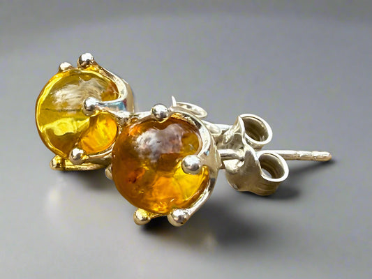 Pair of amber stone earrings with silver settings on a wooden surface