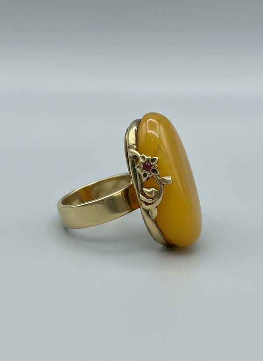 Gold ring with a yellow stone on a wooden surface