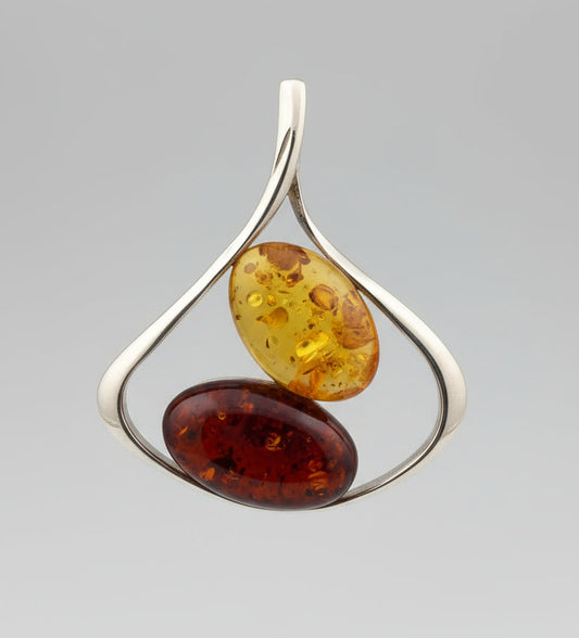 Silver pendant with two amber stones on a wooden surface