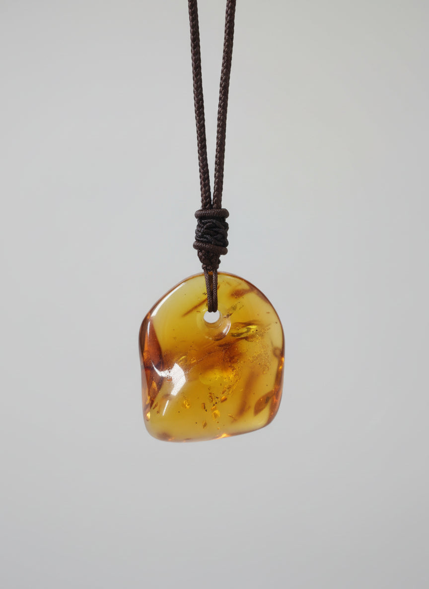 Amber pendant on a string against a light background