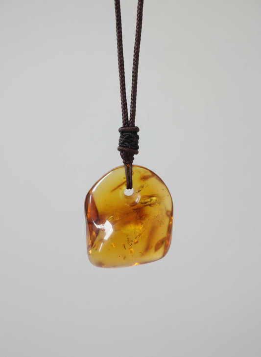 Amber pendant on a string against a light background