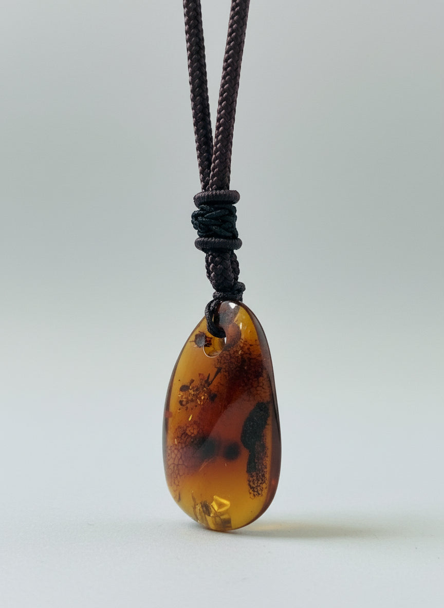 Brown amber stone on a string against a light background