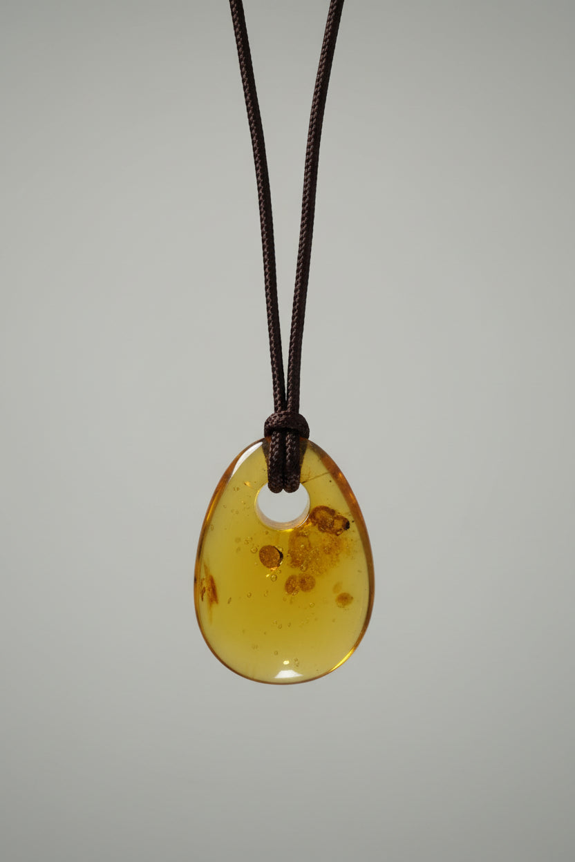 Amber pendant on a string against a light gray background