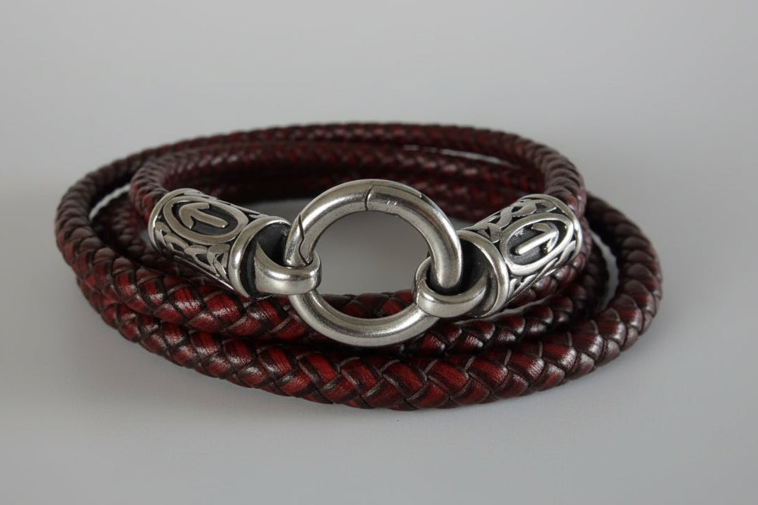 Red braided leather bracelet with a silver clasp on a light background