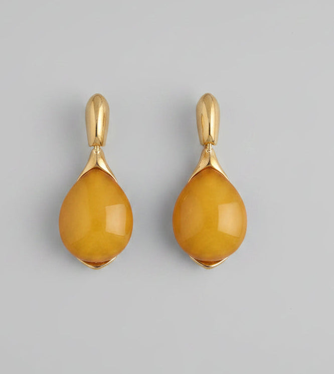 Two yellow teardrop-shaped pendants with gold loops on a white background