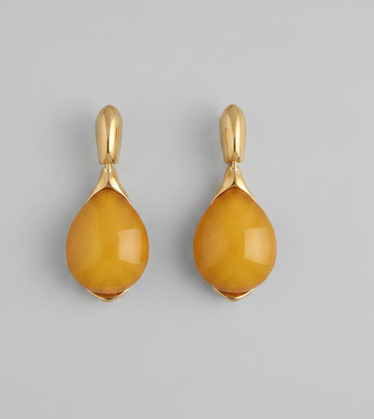 Two yellow teardrop-shaped pendants with gold loops on a white background