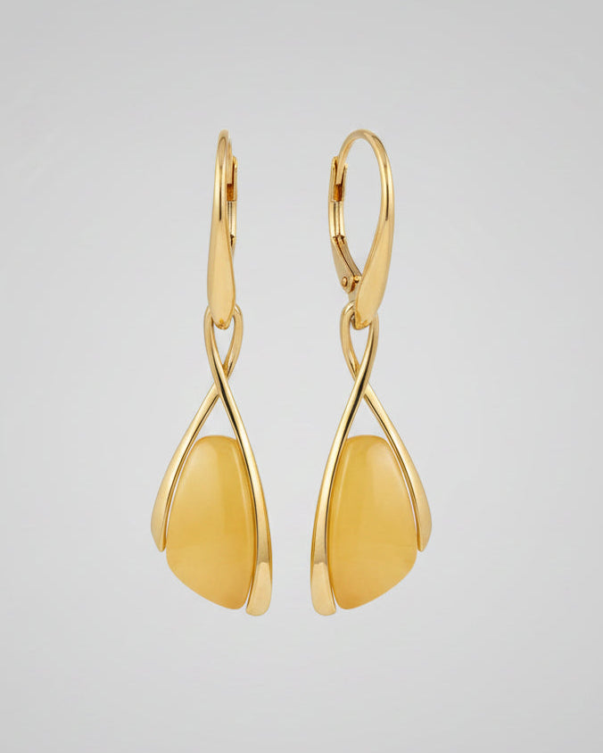 Gold earrings with yellow stones on a wooden surface