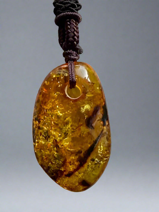 Amber pendant on a braided cord against a textured beige background
