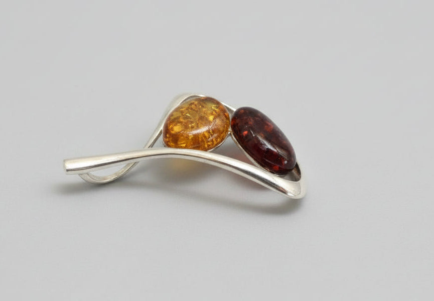 Silver brooch with amber stones on a wooden surface