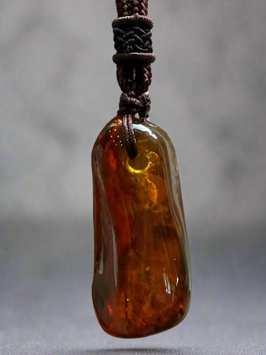 Amber pendant on a brown cord against a beige background