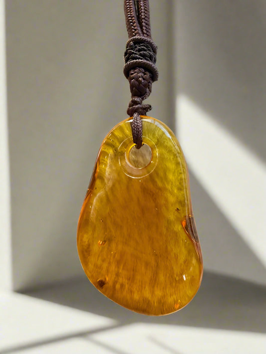 Amber pendant on a brown cord against a textured beige background