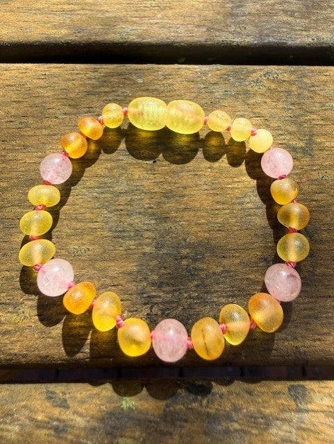 Bracelet with yellow and pink beads on a wooden surface