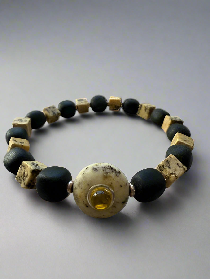 Bracelet with black, gold, and yellow beads on a gray background