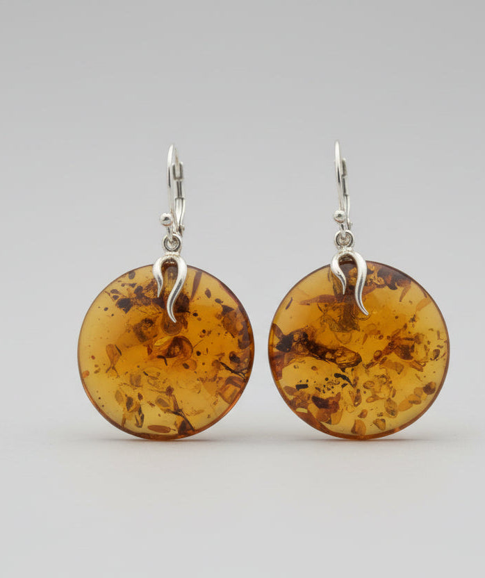 Pair of amber disc earrings with silver hooks on a light gray background