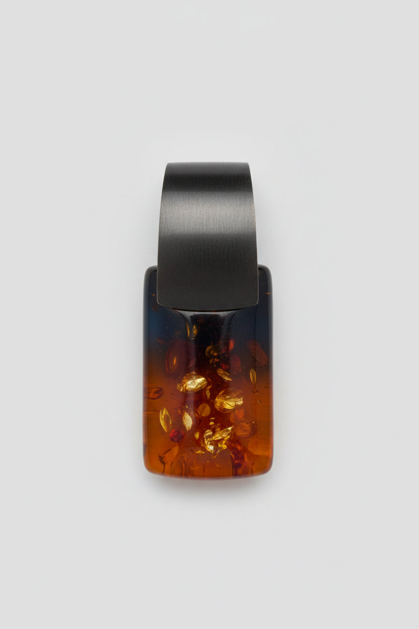 Resin ring with black and amber design on a wooden surface