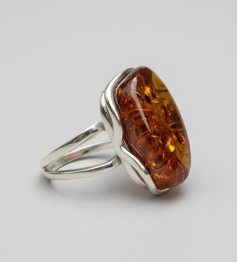 Silver ring with a large amber stone on a wooden surface