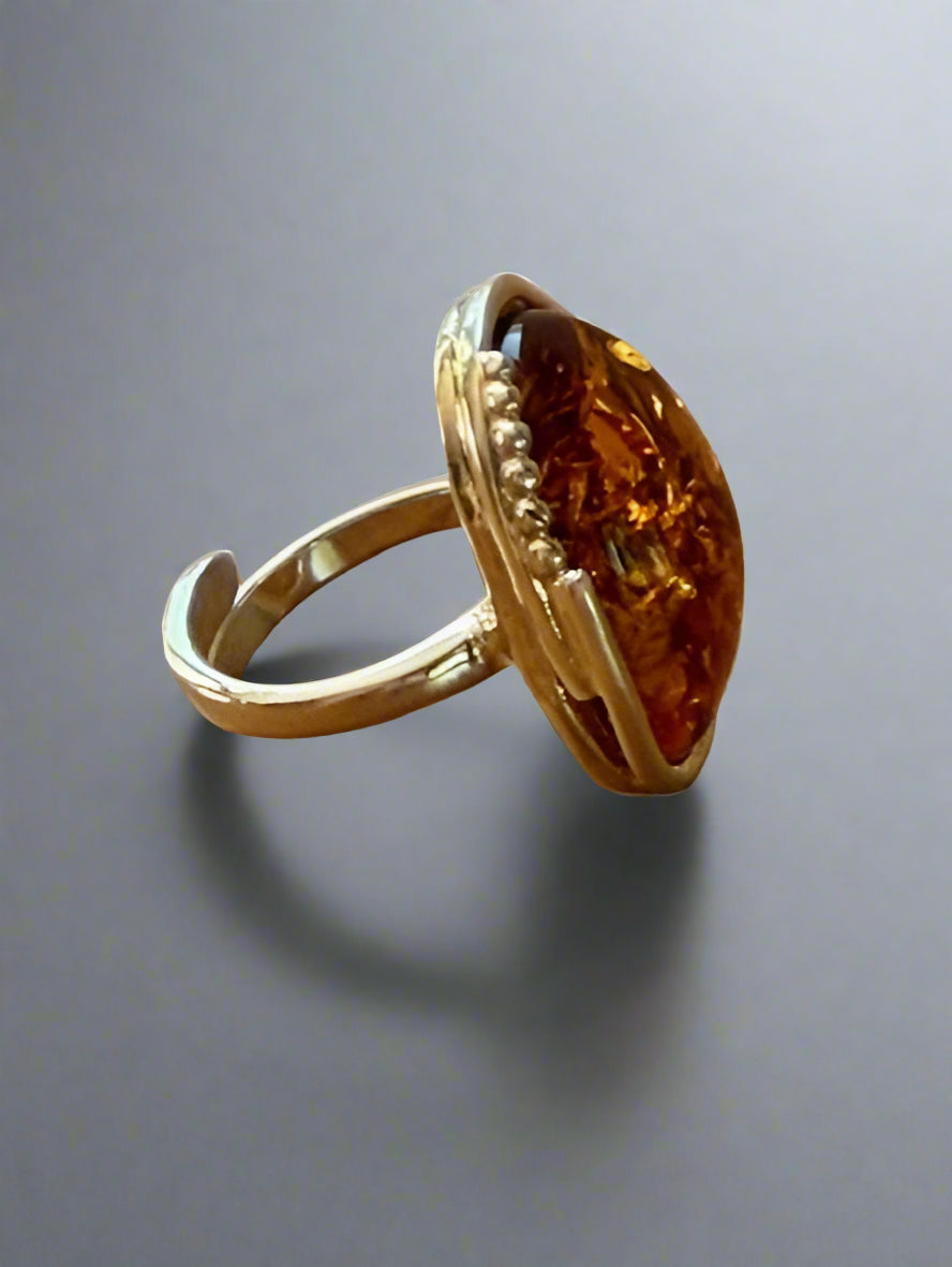 Gold ring with a large amber stone on a wooden surface