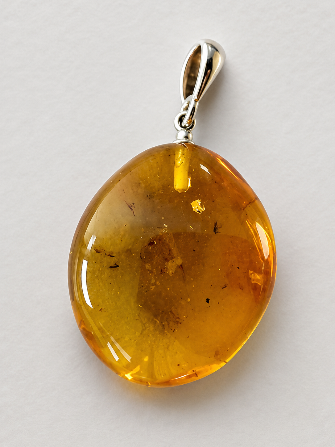 Amber pendant with silver bail on a light gray background