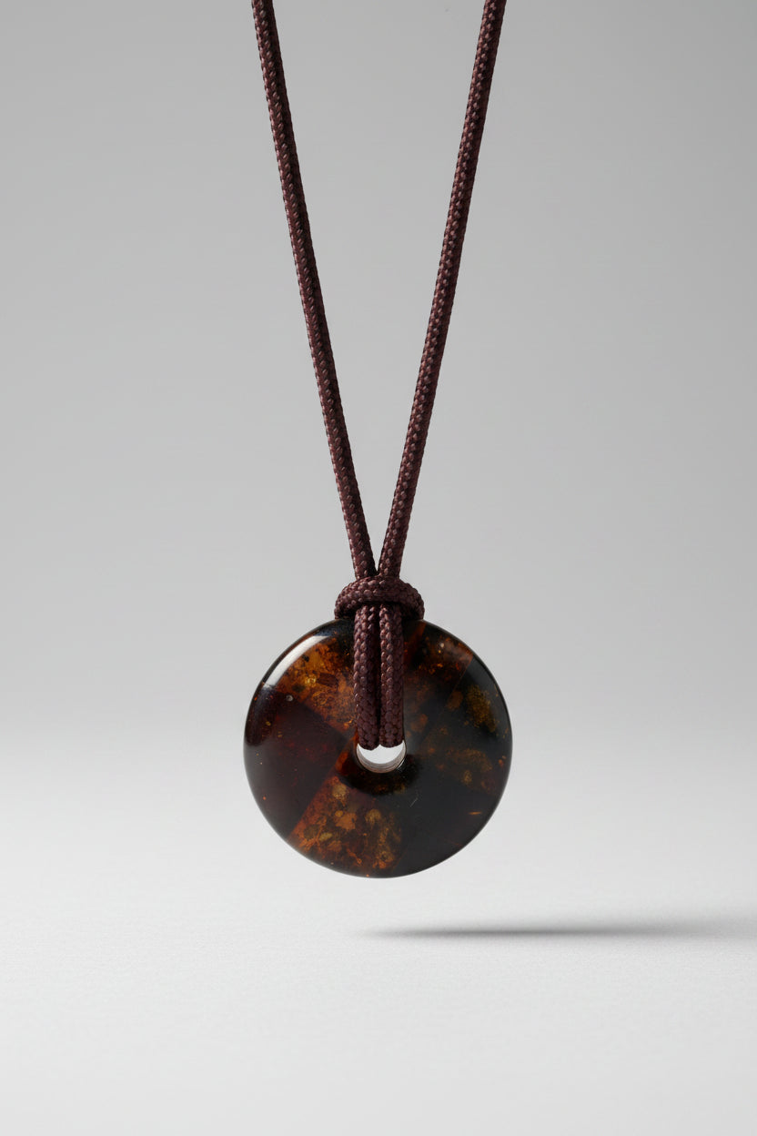 Round amber pendant on a brown cord against a white background