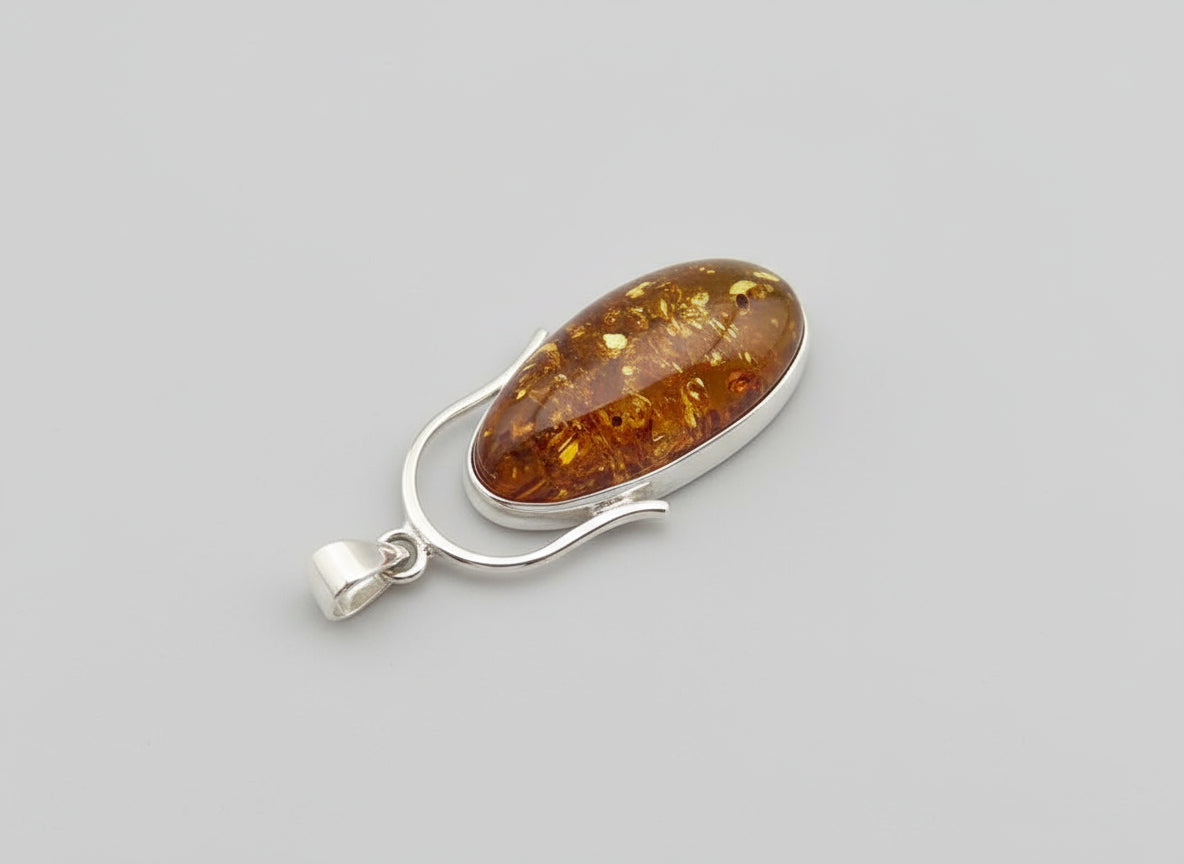 Amber pendant with silver setting on a wooden background