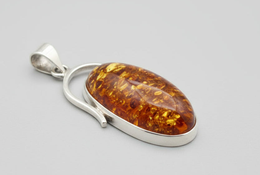 Amber pendant with silver setting on a wooden surface