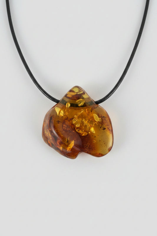 Amber pendant on a black cord against a textured gray background