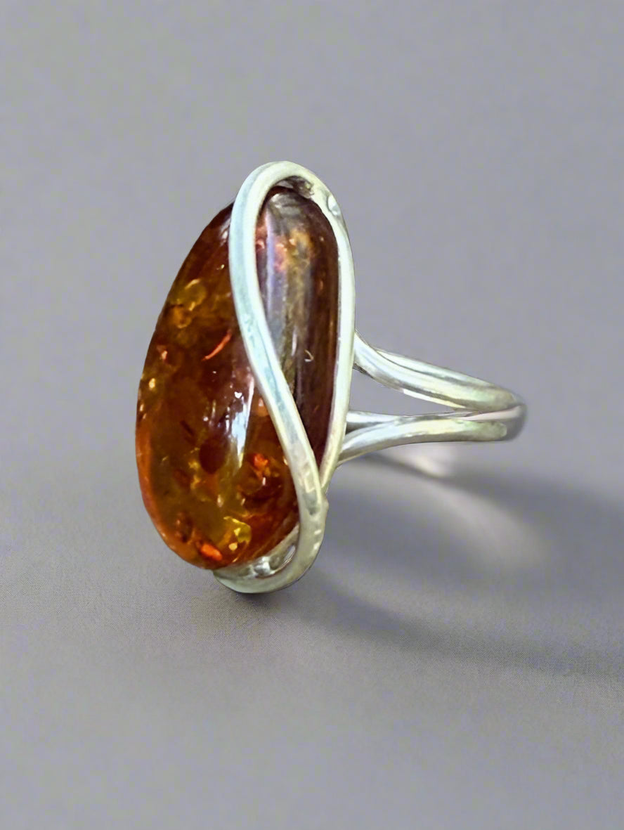 Amber ring with silver band on a stone surface