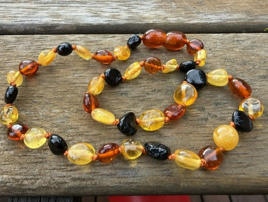 Necklace with amber and black beads on a wooden surface
