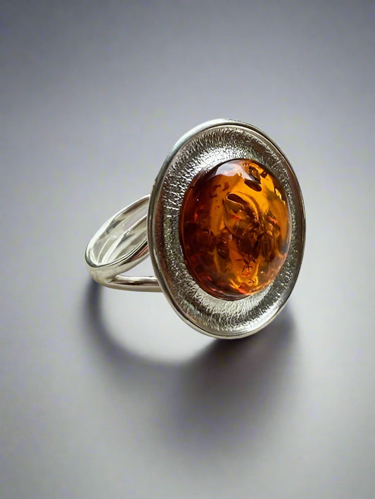 Silver ring with a amber stone on a textured surface
